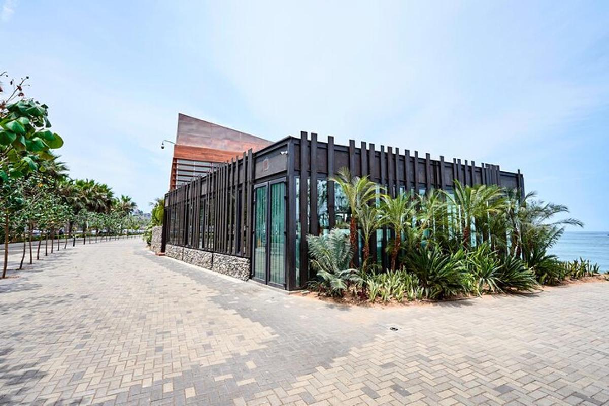 un edifici negre amb plantes al costat de l'oceà