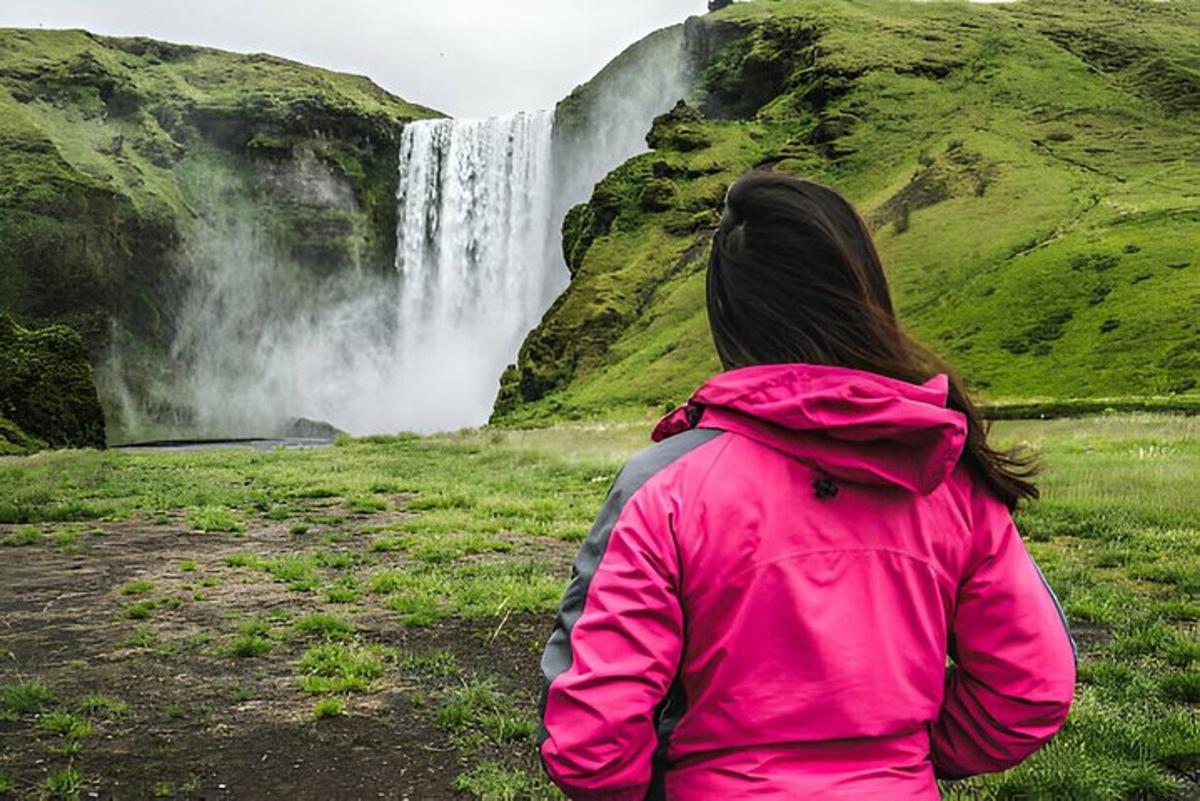 una donna con una giacca rosa che guarda una cascata