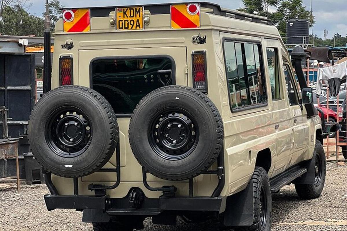 ein hellbrauner Jeep mit großen Rädern, der auf einem Parkplatz geparkt ist
