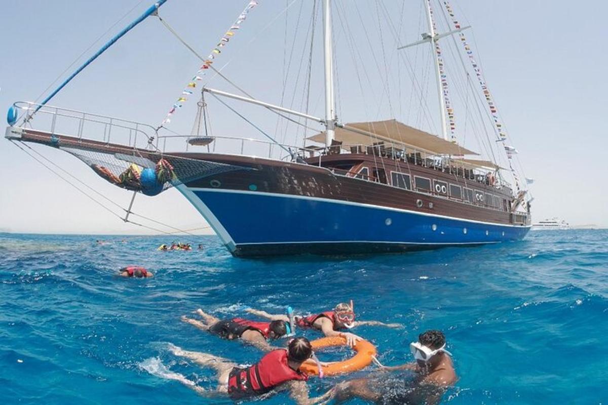 een groep mensen die naast een boot in de oceaan zwemt