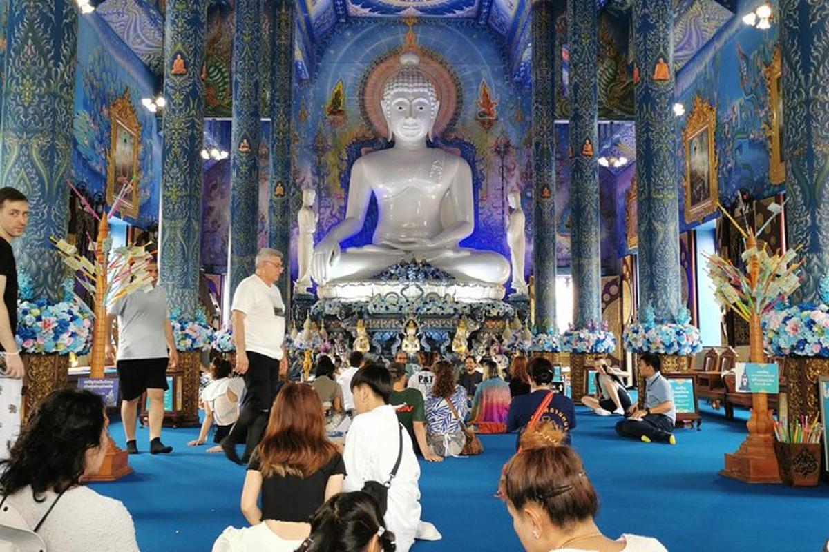 una folla di persone in una grande stanza con un Buddha gigante