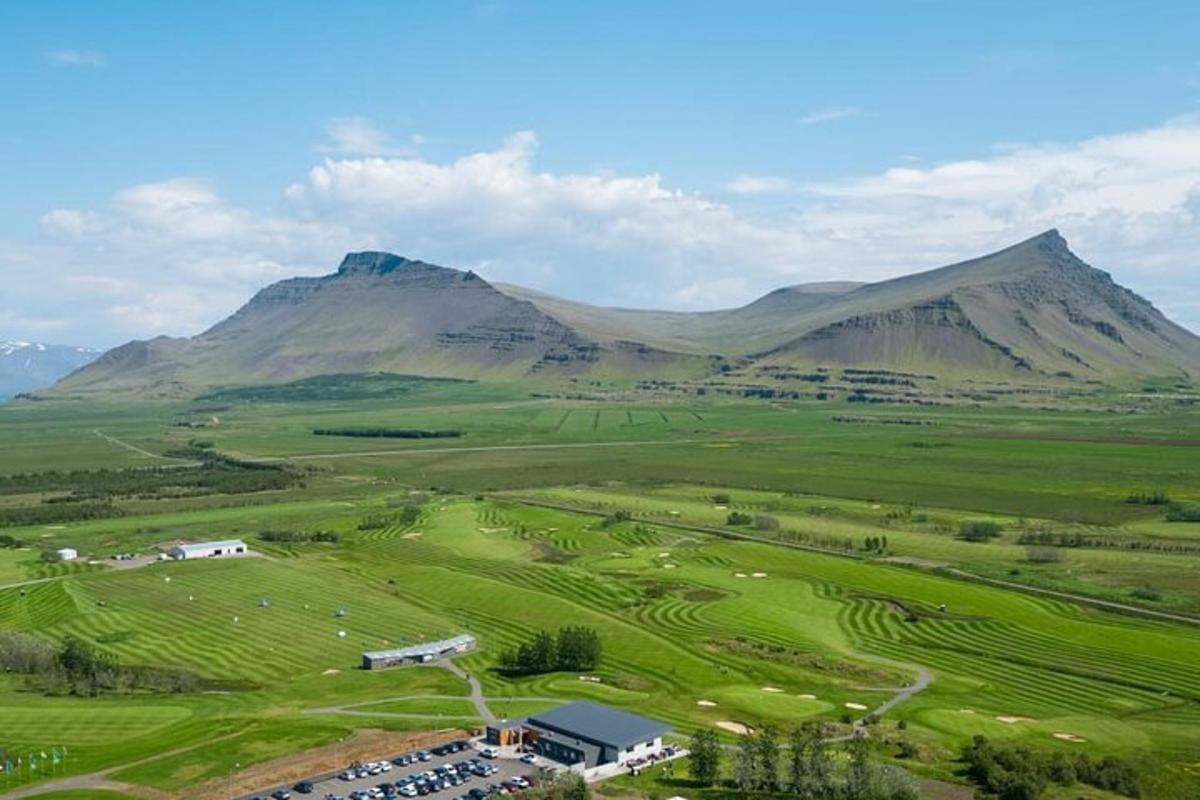 Loftmynd af golfvelli með fjöllum í bakgrunni
