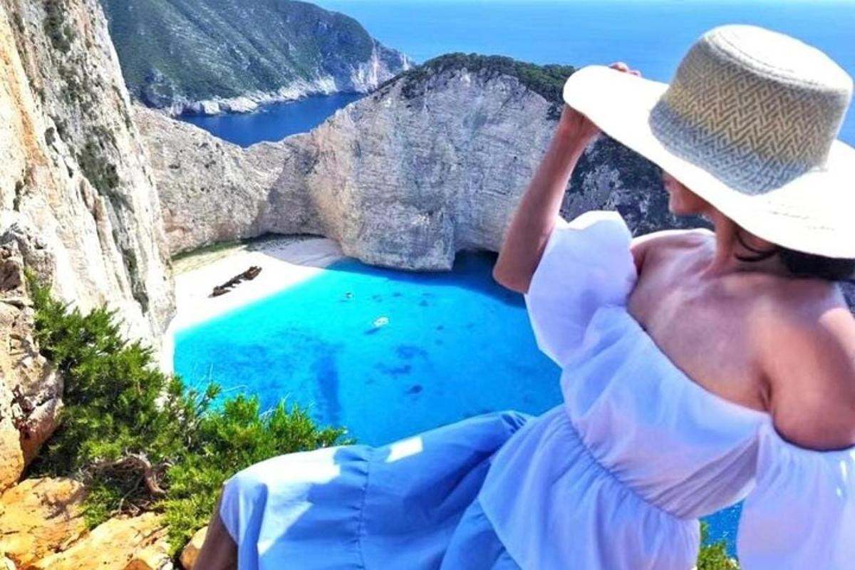 žena v klobúku sediaca na útese a pozerajúca sa na jazero