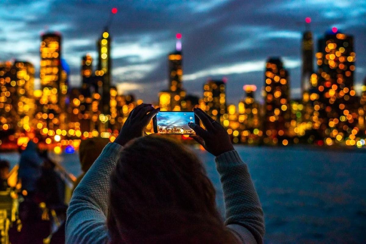 a woman taking a picture of a city with her cell phone