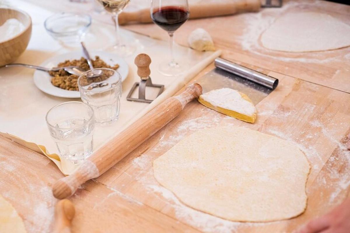 una taula amb una taula de tallar amb massa i copes de vi