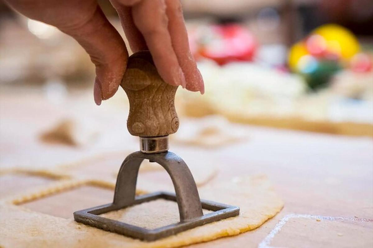 una persona tallant un tros de massa amb un tallador de pizza