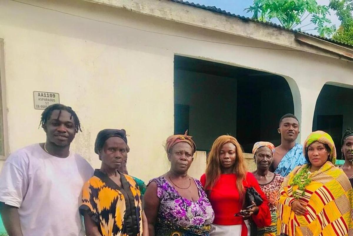un grup de persones dretes davant d'una casa
