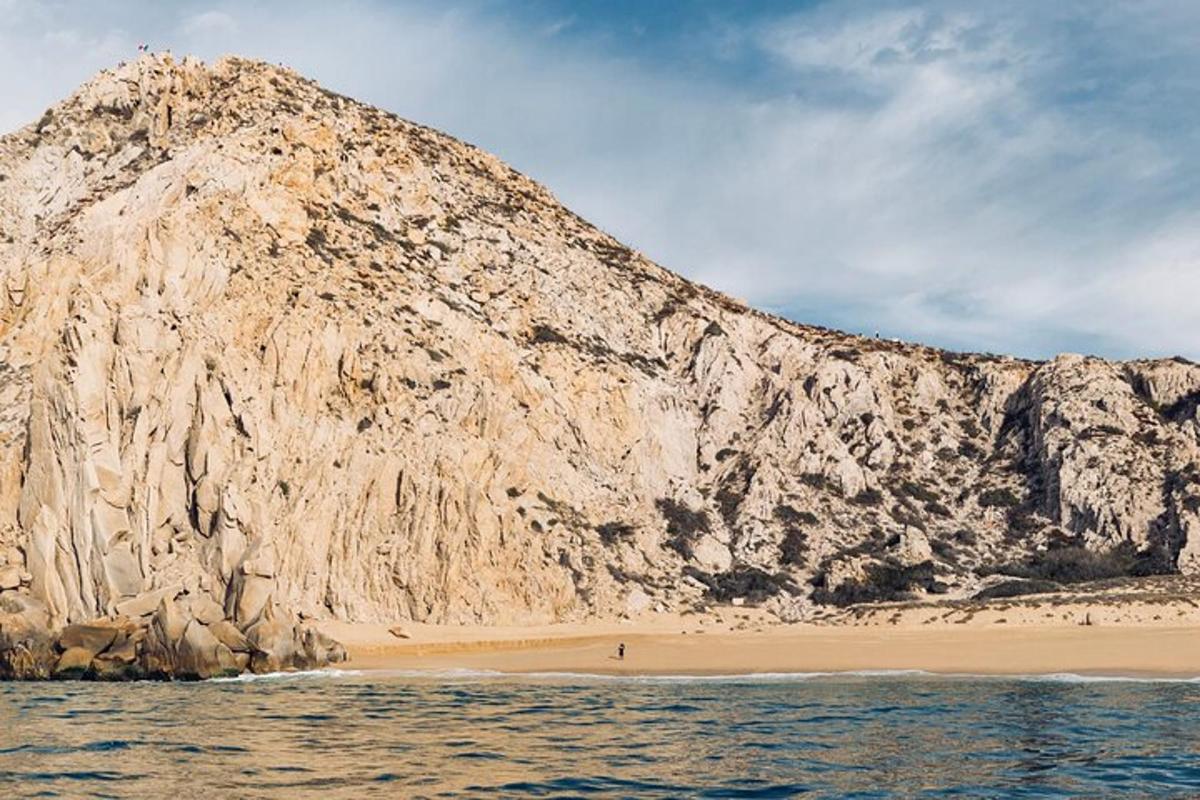 una grande montagna rocciosa accanto a una spiaggia sabbiosa