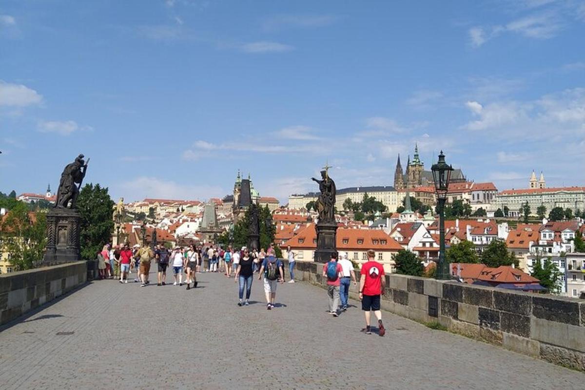 cilvēku grupa, kas iet pa tiltu pār pilsētu