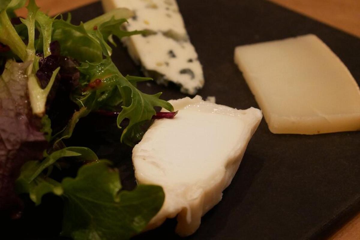 Un trozo de queso y una ensalada en un plato negro
