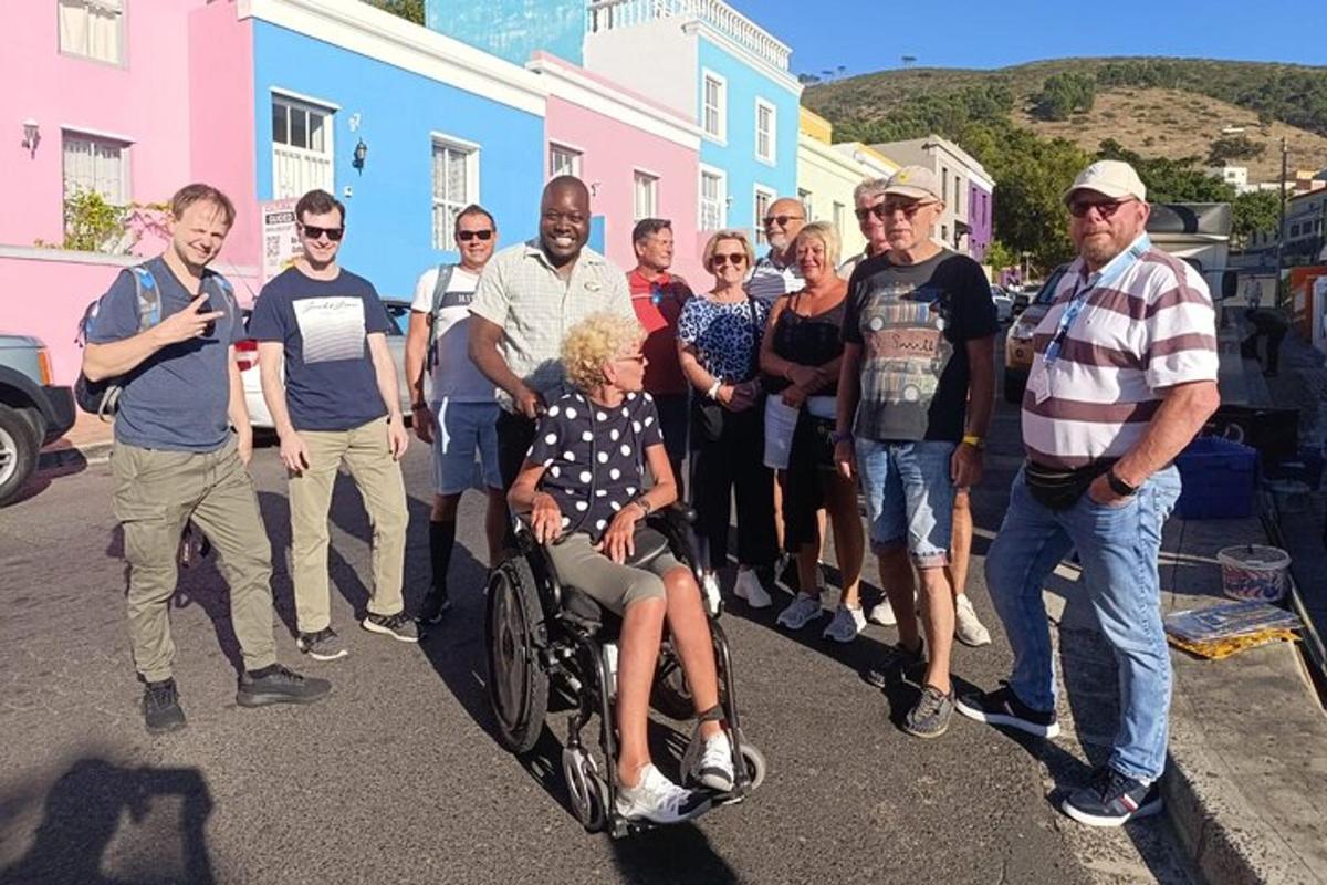 un grup de oameni care pozează pentru o fotografie cu o persoană într-un scaun cu rotile