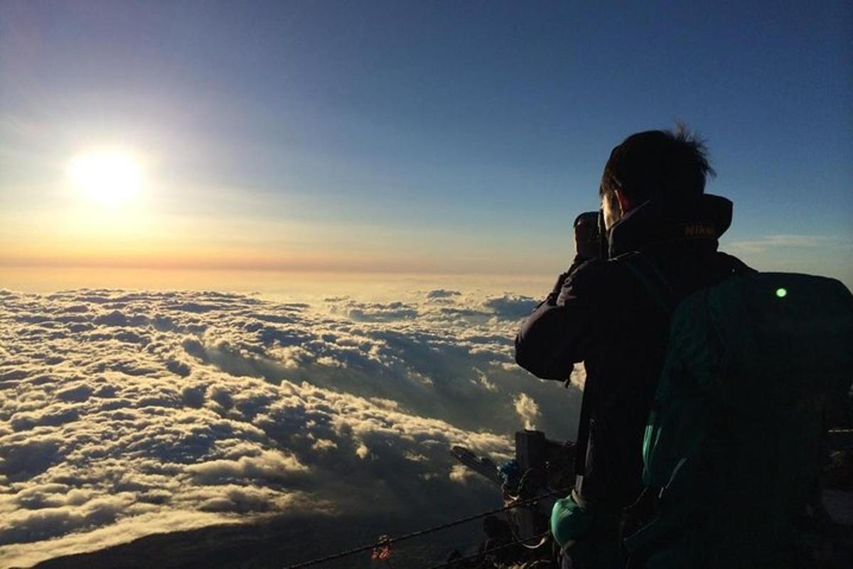 una persona dreta al cim d'una muntanya mirant la posta de sol