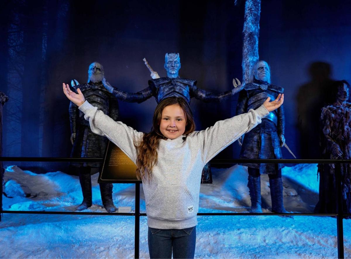 a little girl standing in front of a group of actors