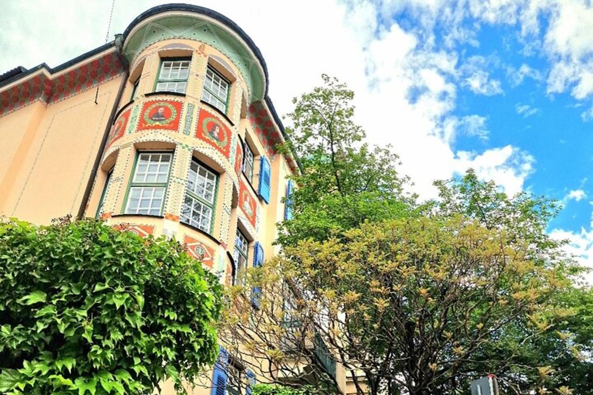 ein hohes orange-grünes Gebäude mit Bäumen davor