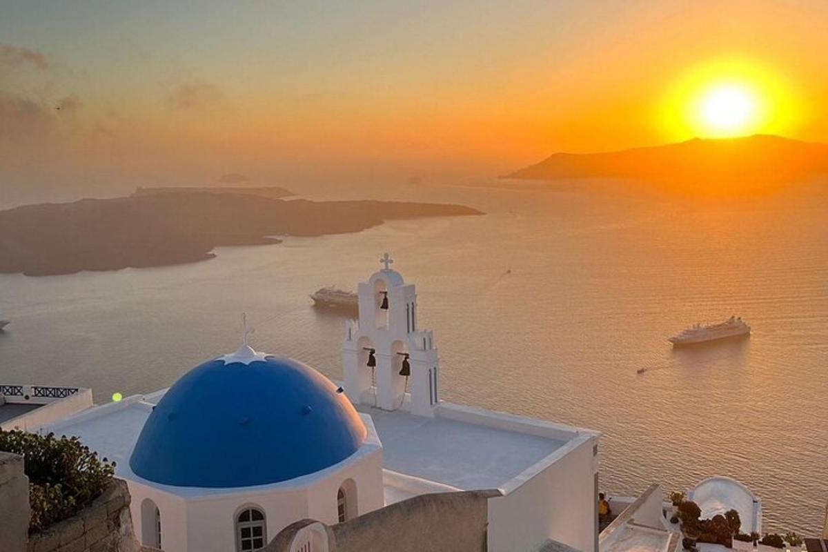 una chiesa con una cupola blu e un tramonto sull'acqua