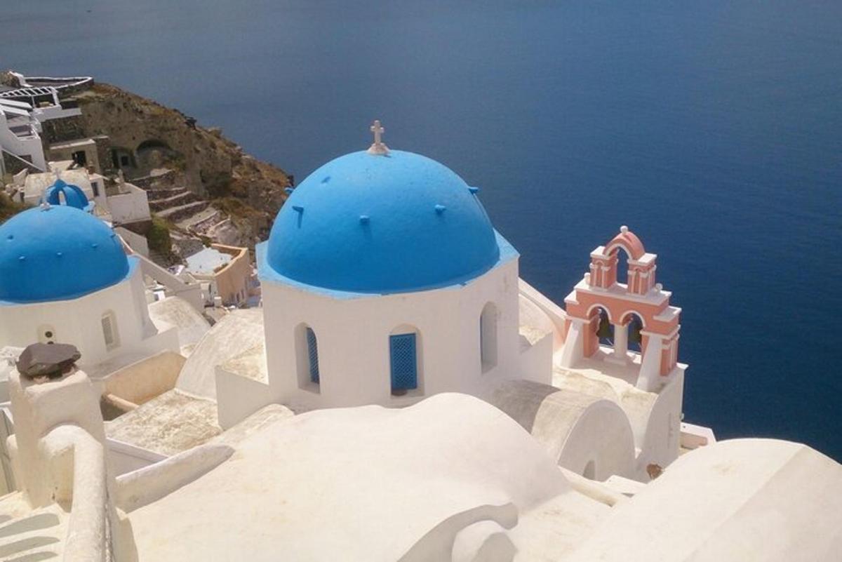 un gruppo di edifici bianchi con cupole blu e l'oceano