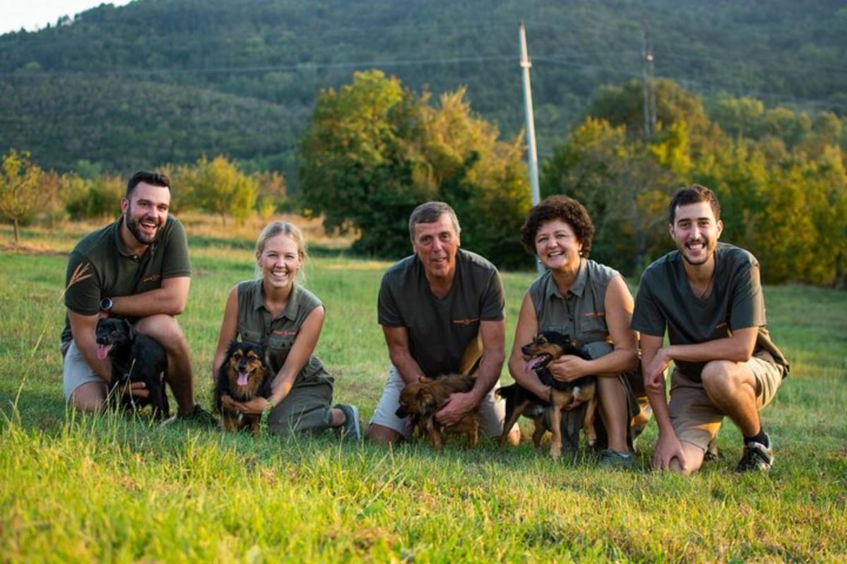 a group of people sitting in the grass with their dogs