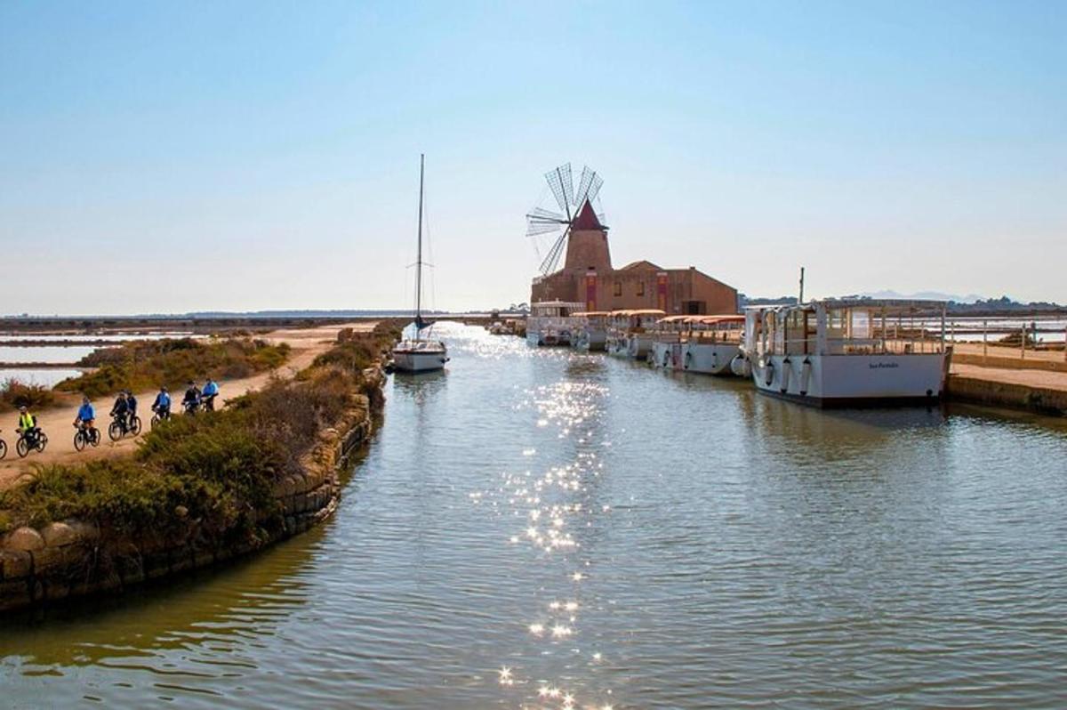 a river with a windmill and people riding bikes on it