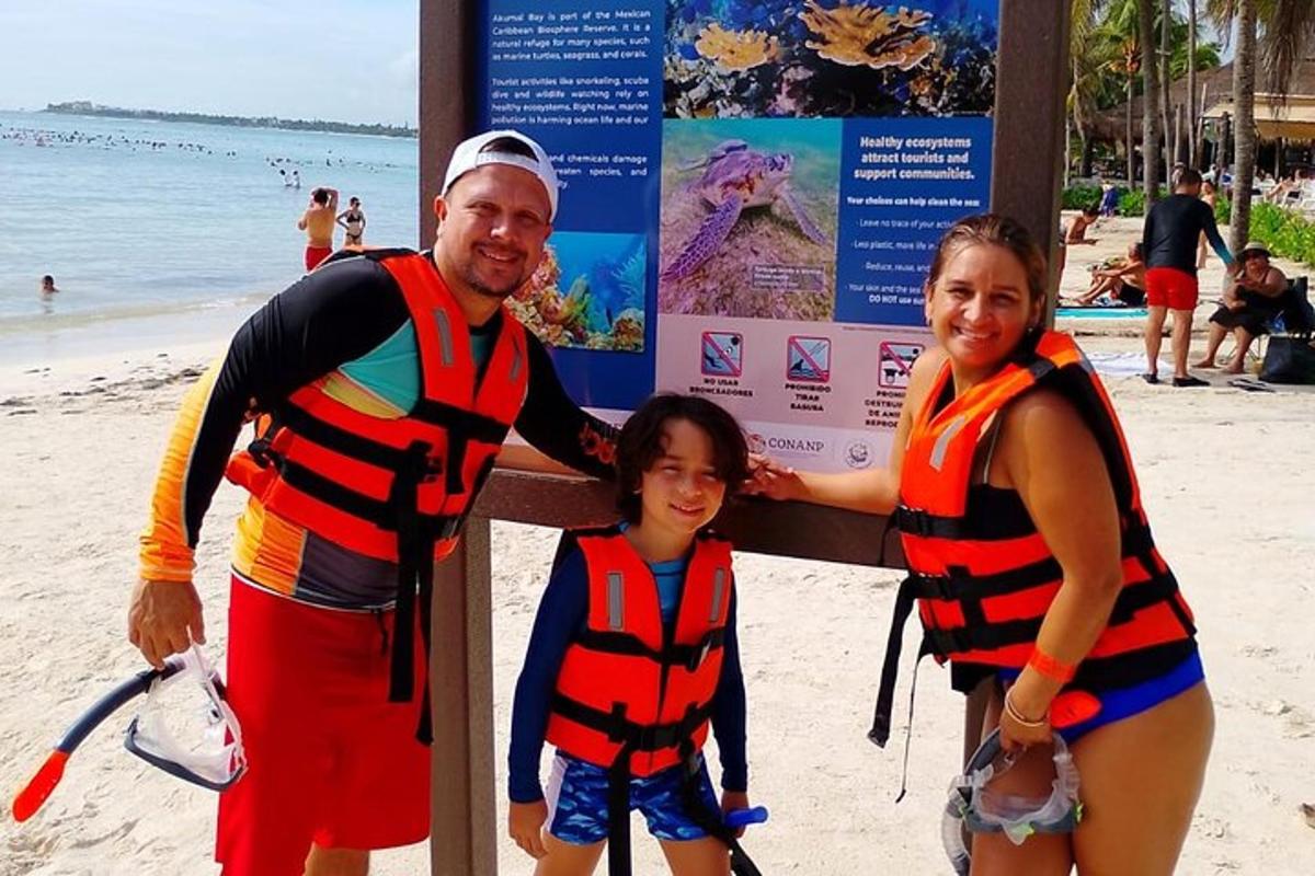 moški, ženska in otrok v rešilnih jopičih na plaži