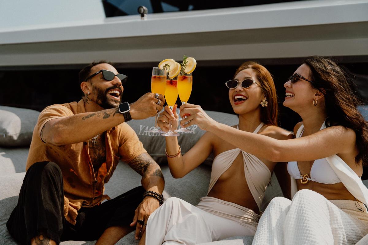 a group of people sitting on a bed drinking drinks