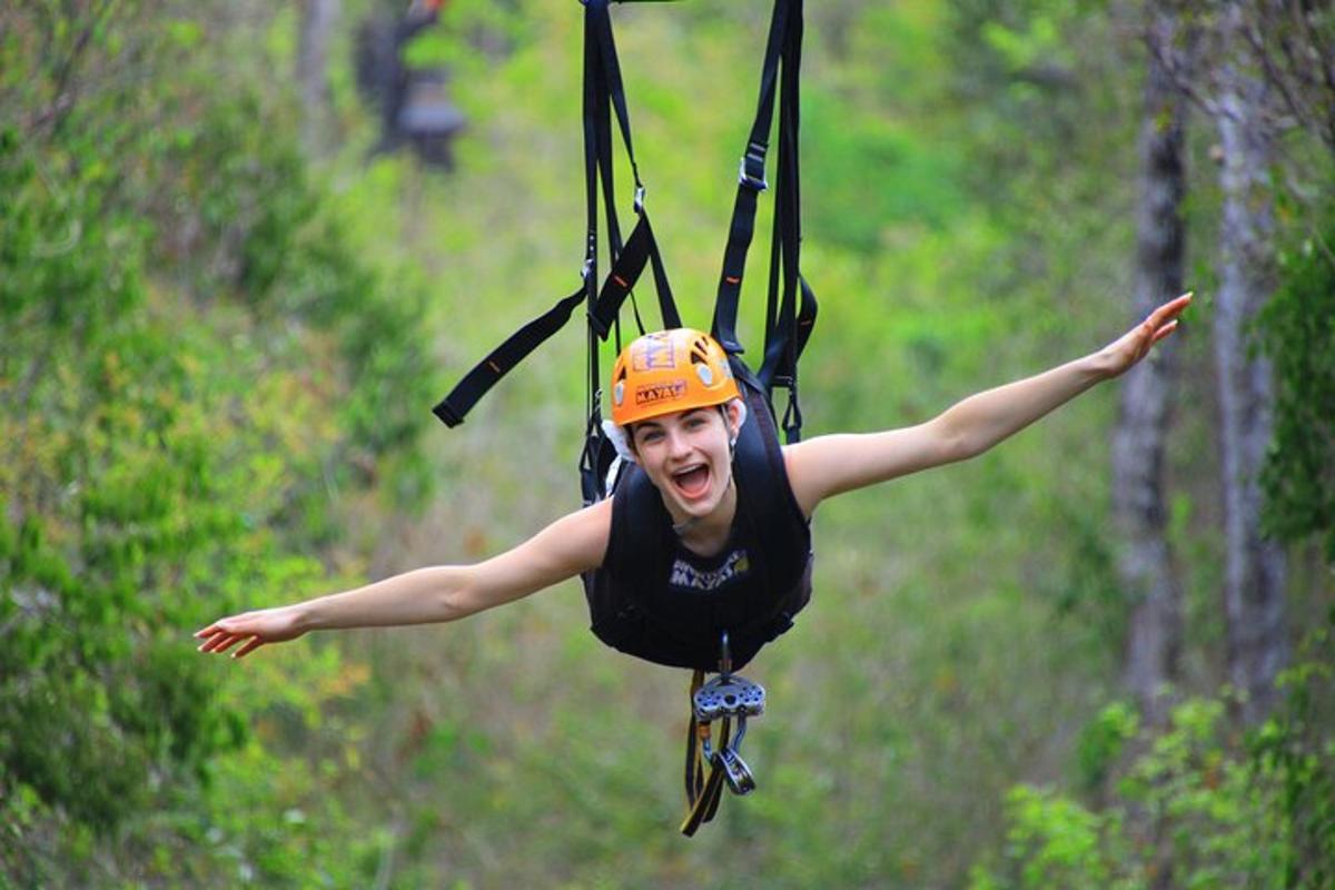a woman in an orange helmet is on a zip line