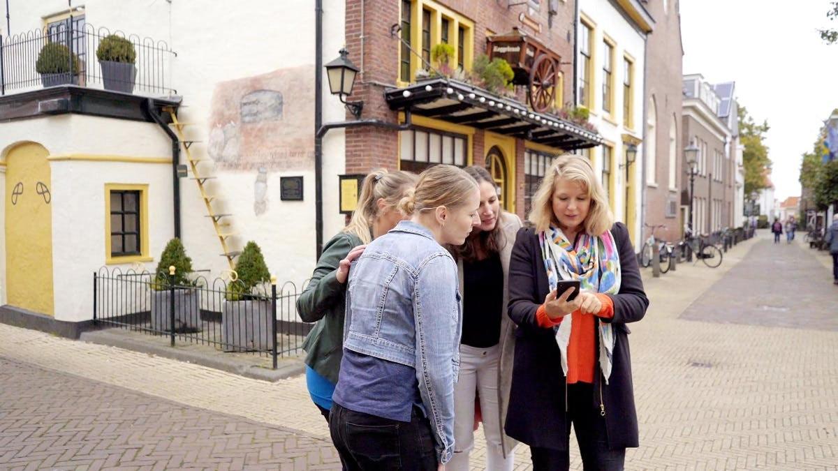 drie meisjes staan op straat en kijken naar een mobiele telefoon