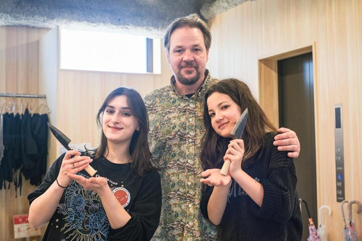 vormiriietuses mees seisab kahe naise kõrval, kes harjavad