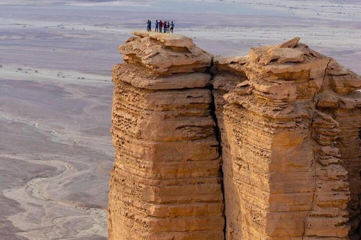 people standing on top of a rock formation in the desert
