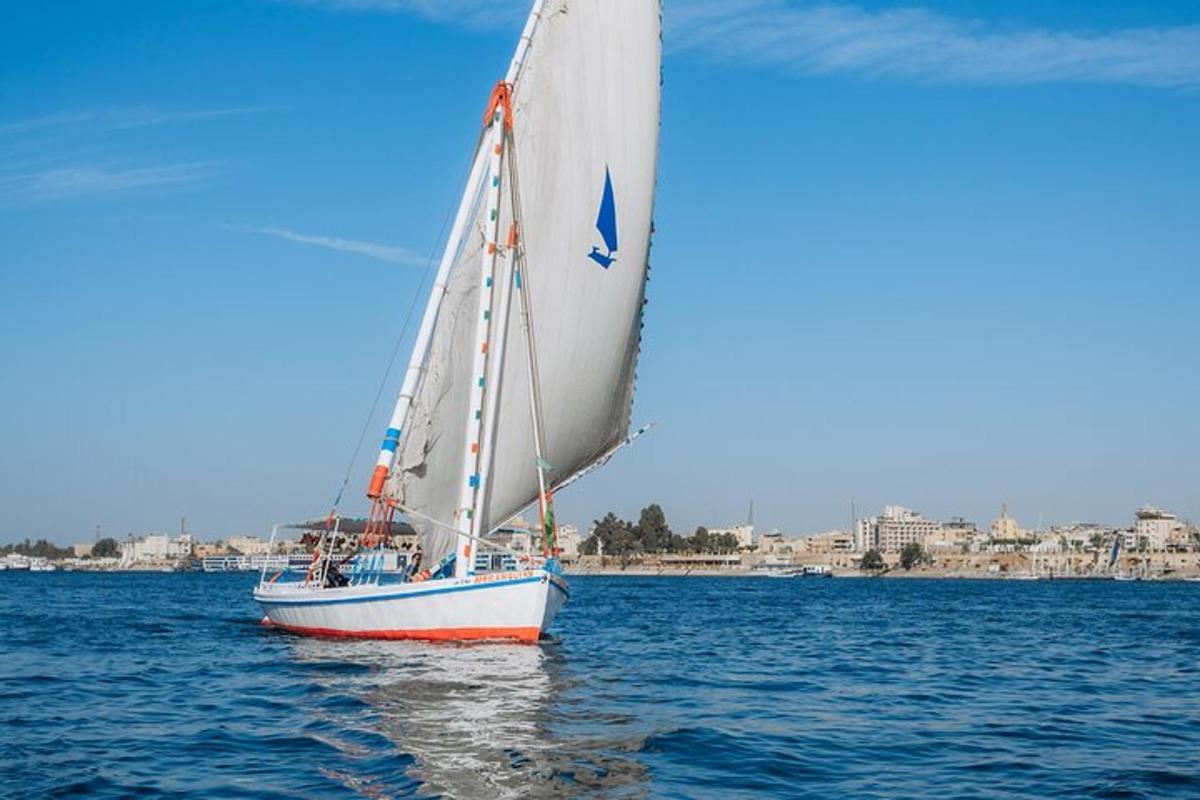 una barca a vela sull'acqua con una città sullo sfondo