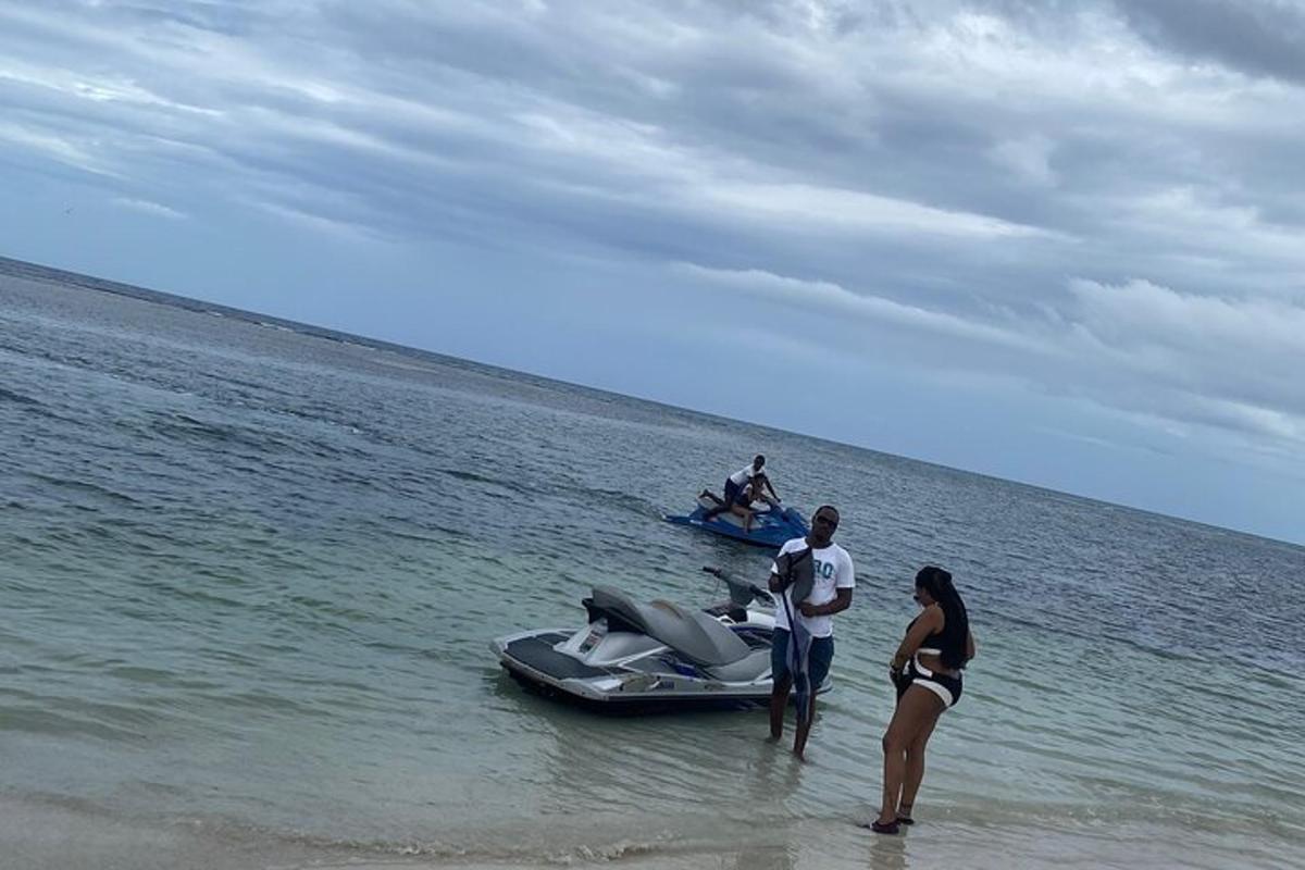 um grupo de pessoas em pé na praia ao lado de um barco a motor