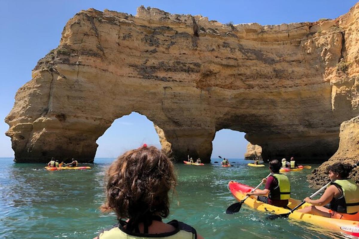 un gruppo di persone che fa kayak vicino a un arco nell'oceano
