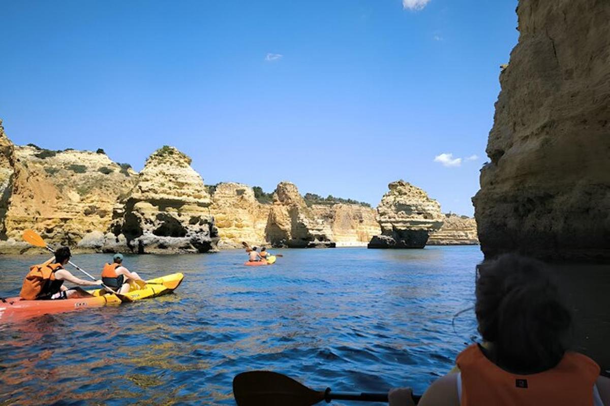 a group of people kayaking on the water near rocks