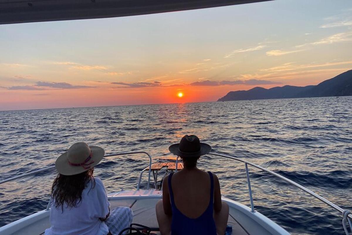 two people sitting on a boat watching the sunset