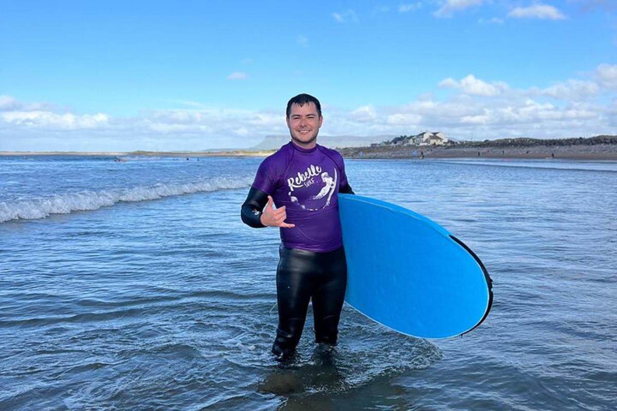 a man standing in the water holding a blue surfboard