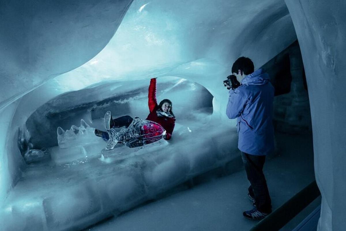 um homem tirando uma foto de uma mulher em uma caverna de gelo