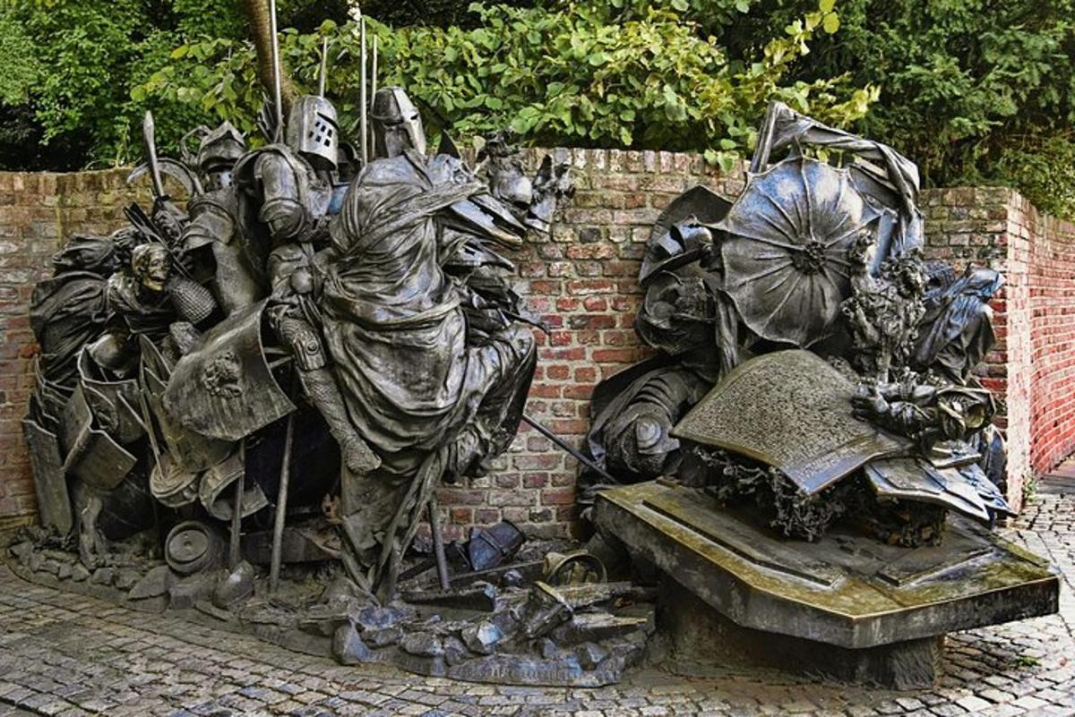 Una estatua de un hombre de pie junto a una pared de ladrillos.