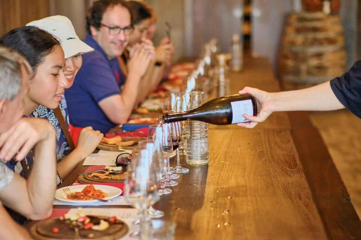 a person pouring a bottle of wine at a table