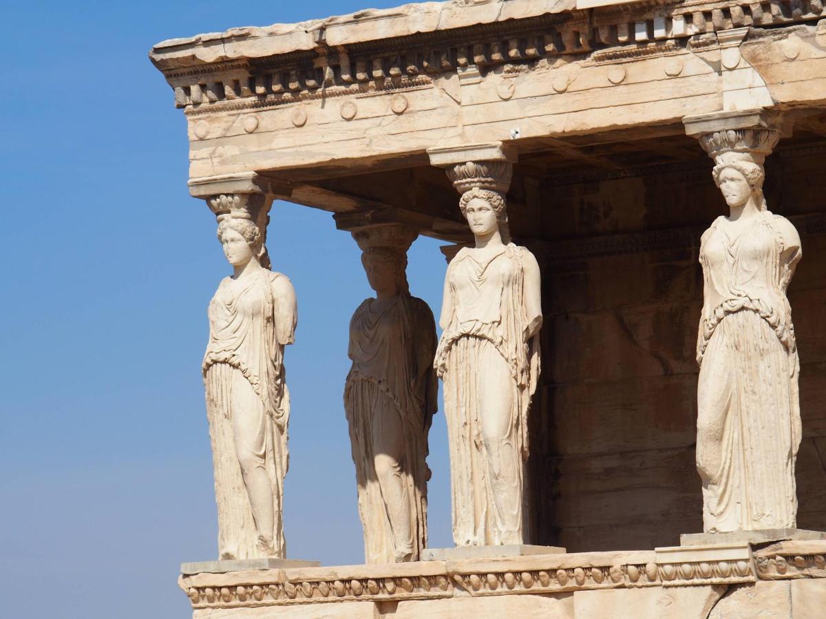 a statue of three women on the side of a building