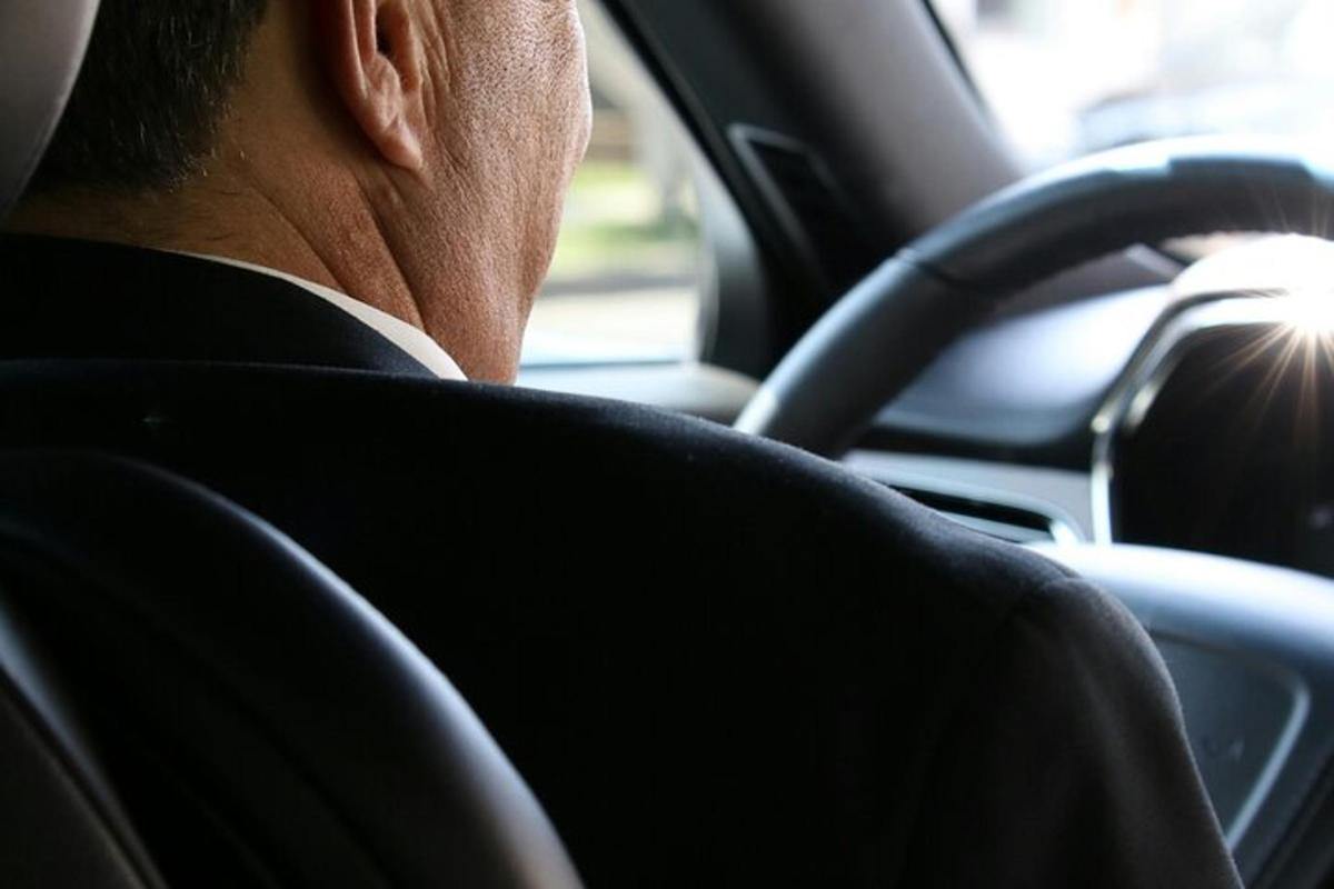 ülikonnas mees istub autos