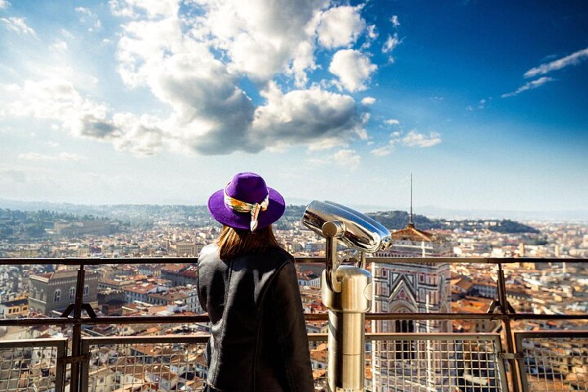 seorang wanita berdiri di atas menara sambil memandangi kota