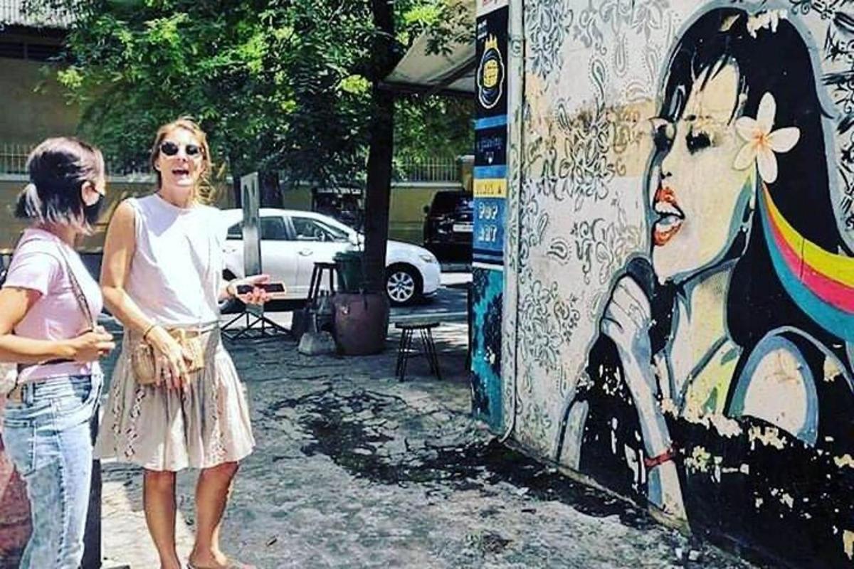 Dos mujeres de pie junto a una pared con una pintura.