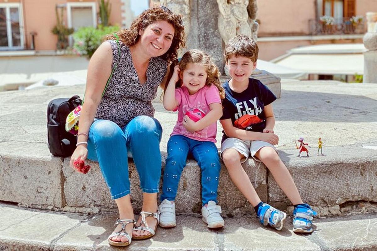 žena a dvě děti sedící na fontáně