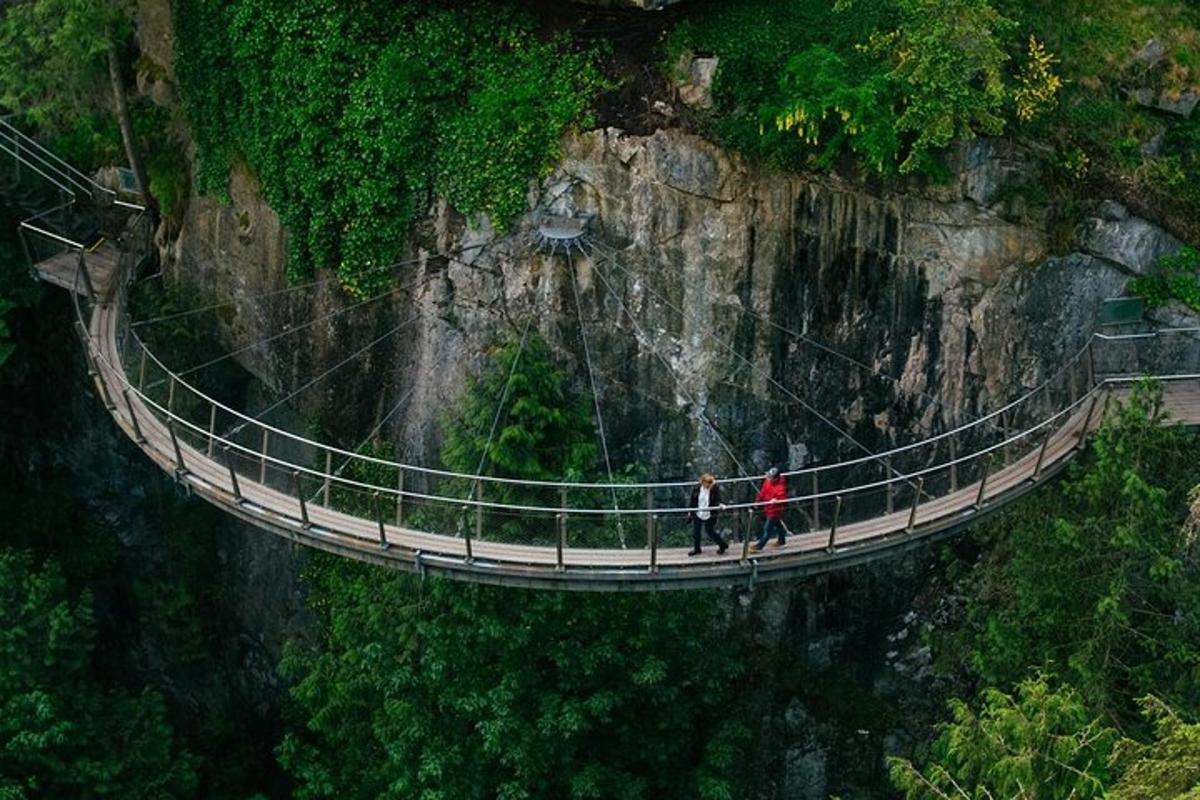 dva lidé jdoucí přes visutý most na hoře