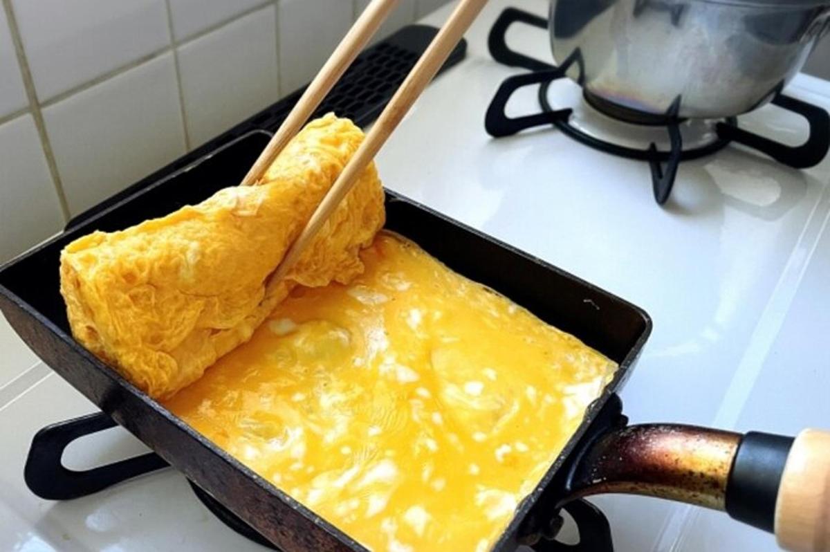 a pan of food on a stove with two wooden sticks