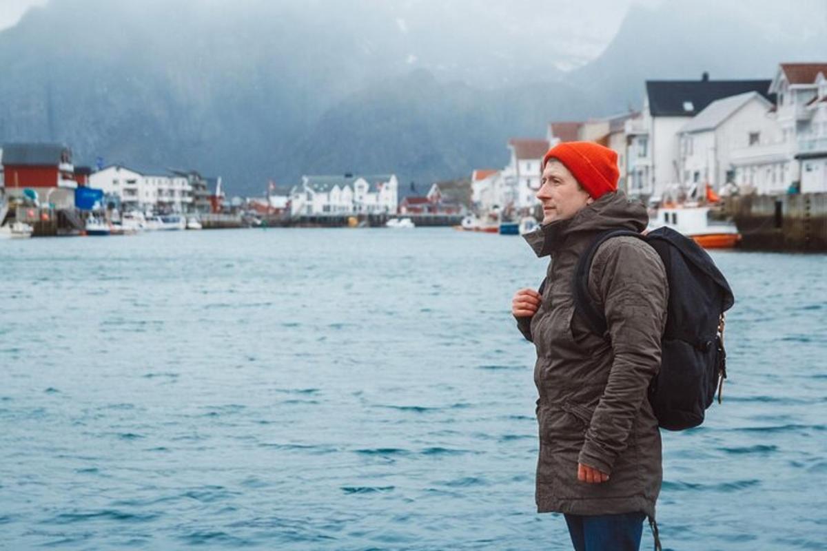 kona með bakpoka stendur við vatnsborð