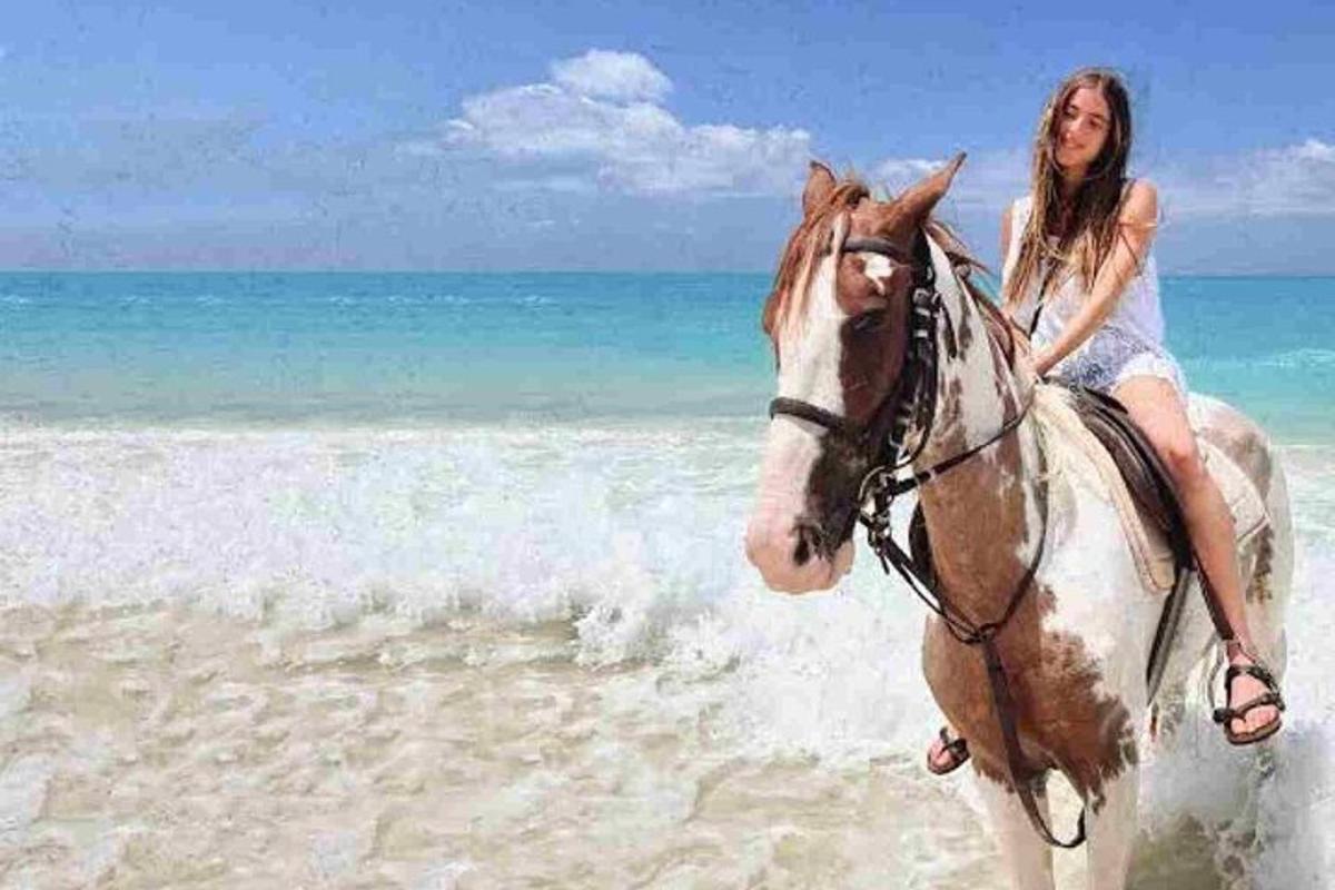 una dona muntant a cavall a la platja