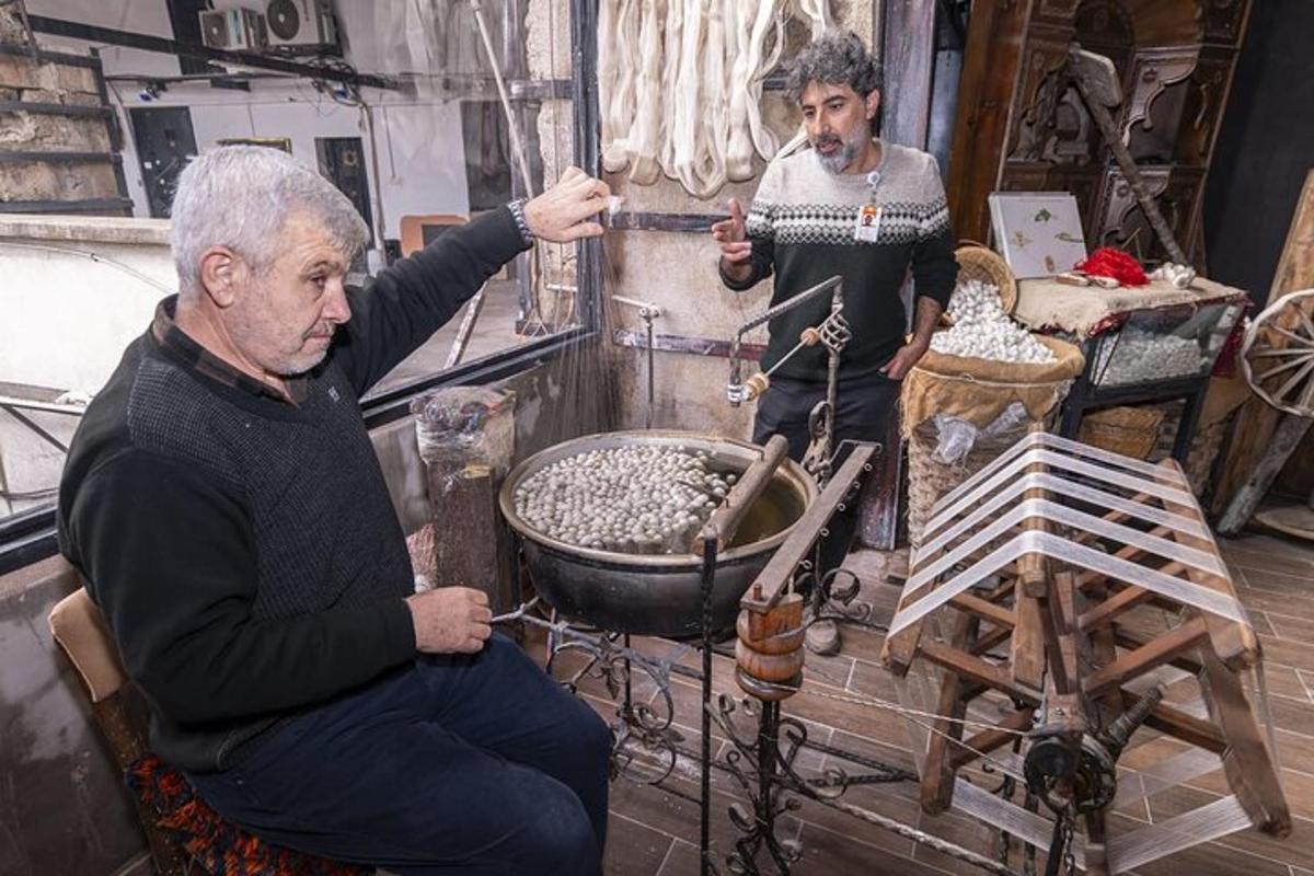 two men sitting in a room with a pot of metals