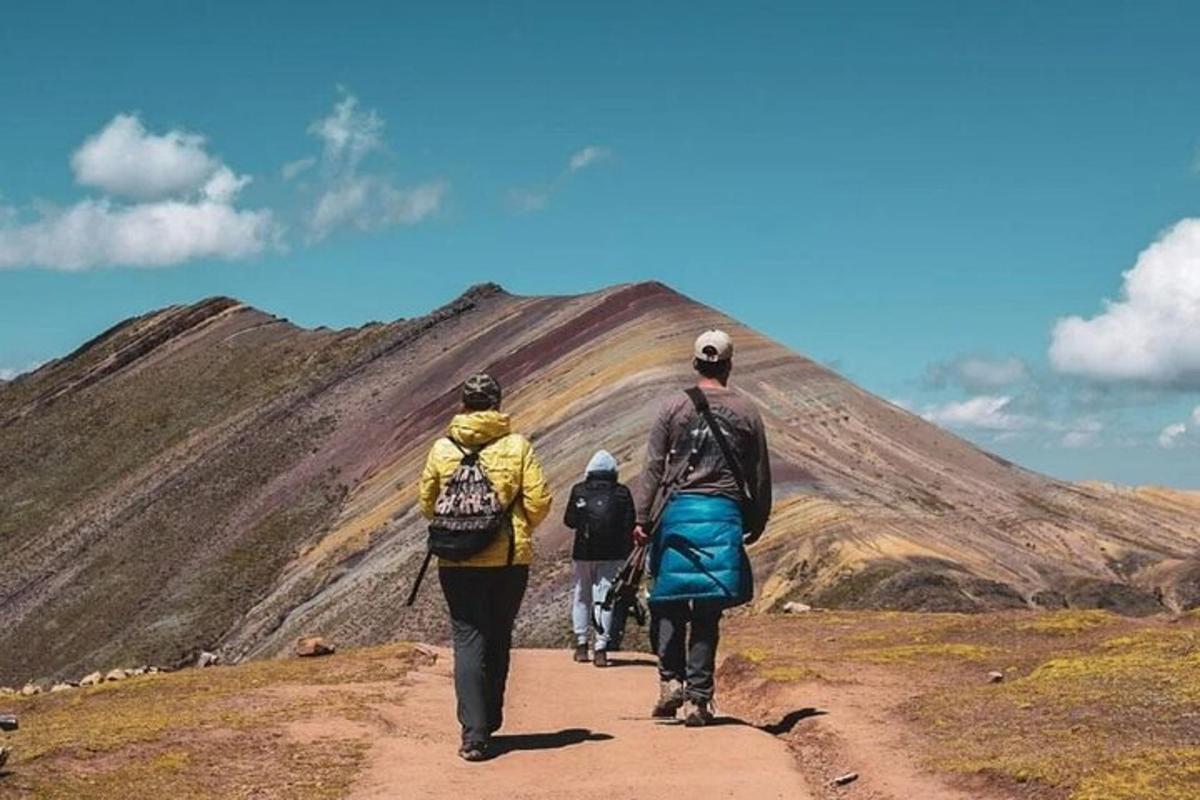 tre persone che camminano lungo una strada sterrata verso una montagna