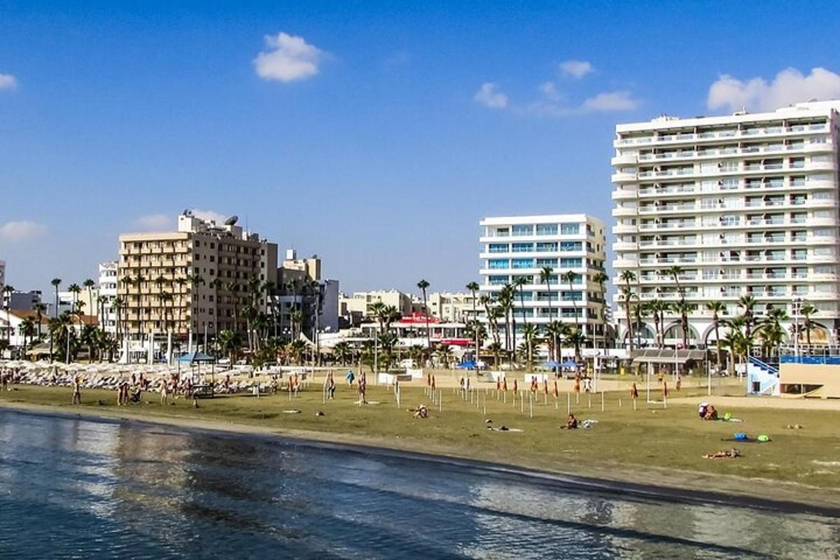 a beach with people laying on the sand and buildings