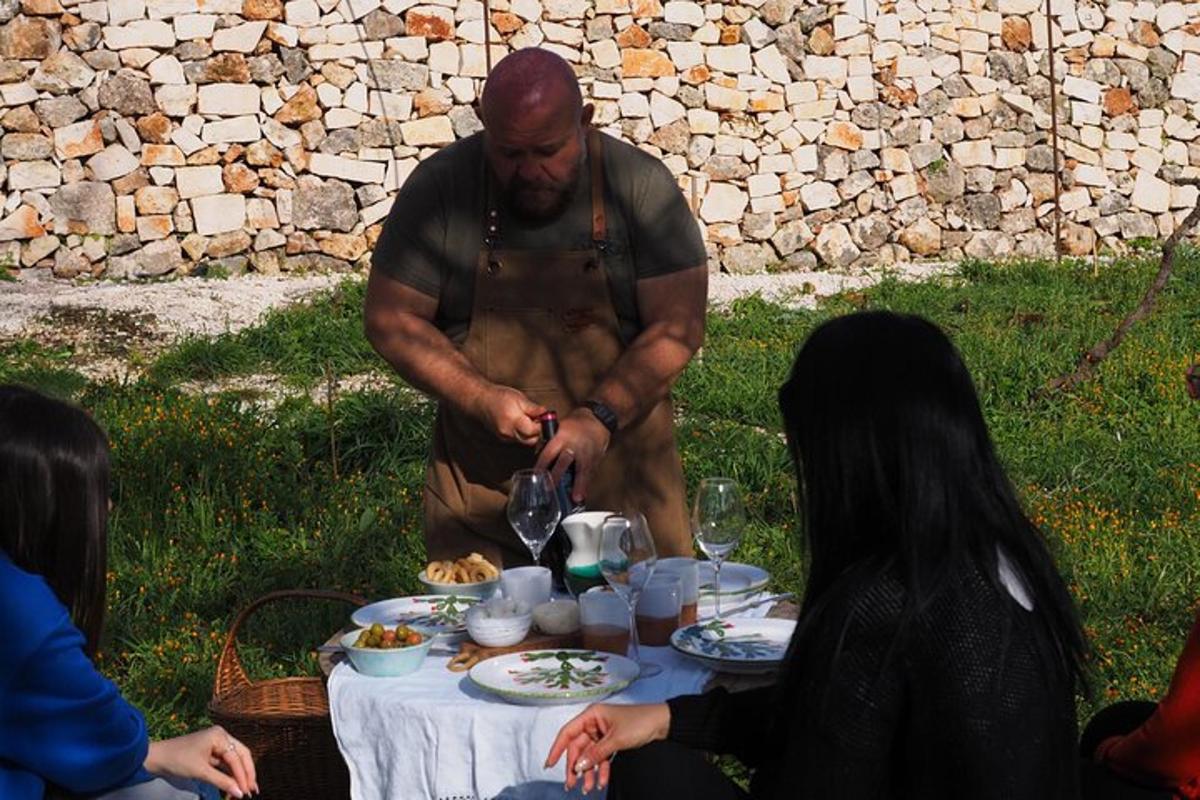 um homem preparando comida em uma mesa com pessoas
